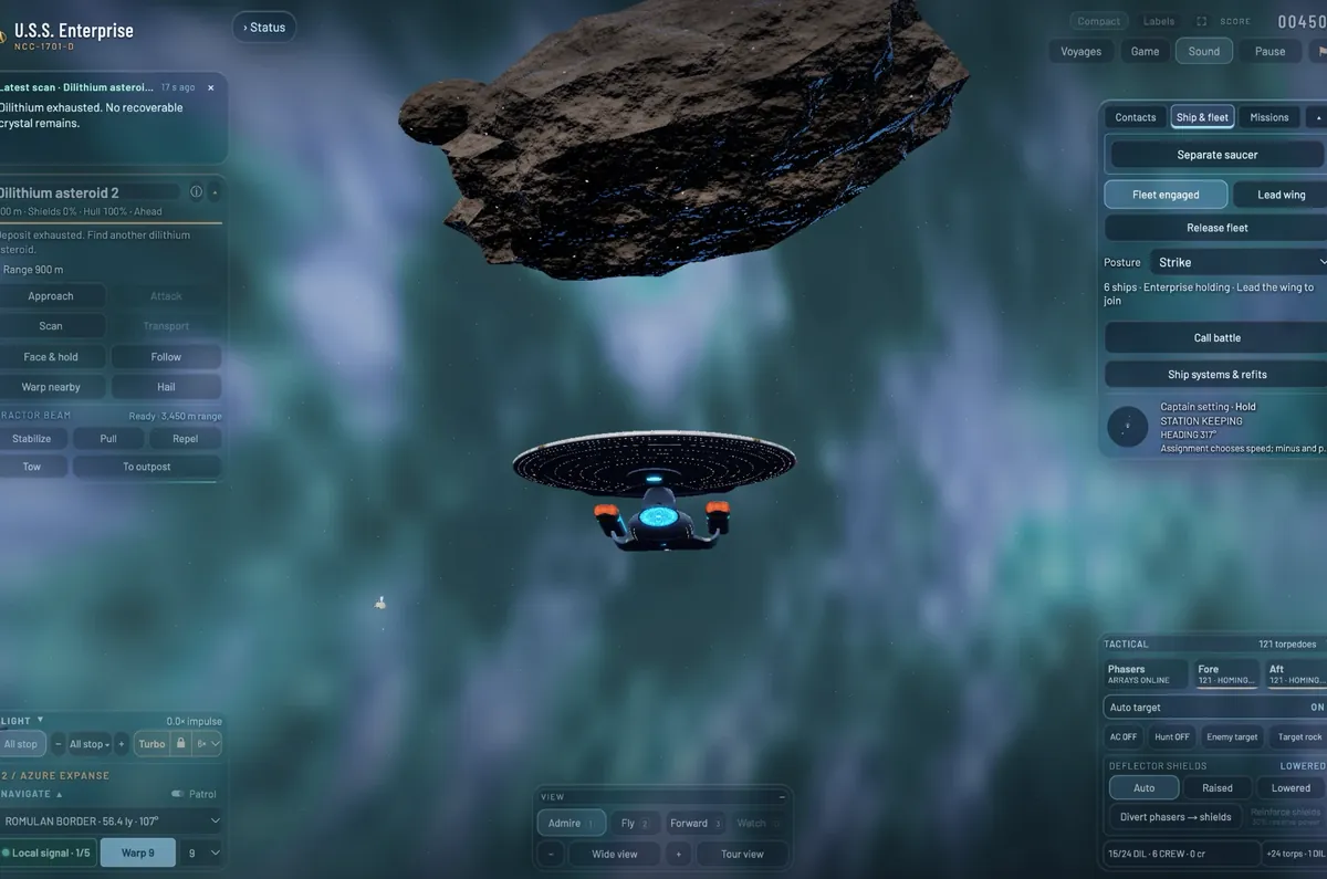 The Enterprise head-on beneath a huge dilithium asteroid, the deflector dish glowing blue.